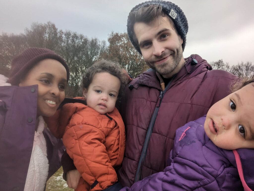 Picture of a family with two parents and two young children dressed in winter gear and standing outside