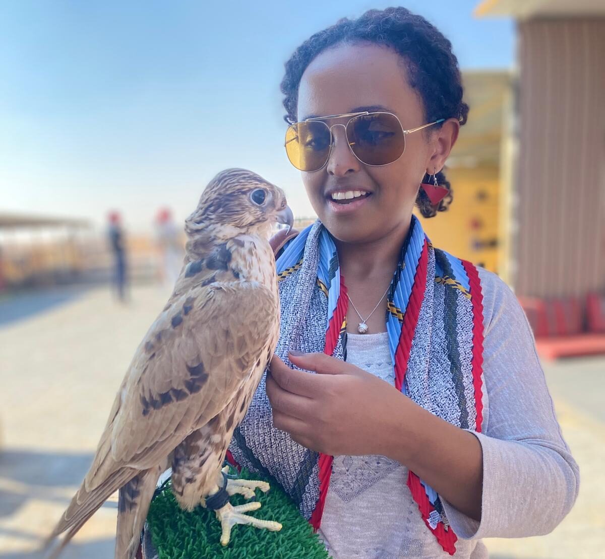 black woman with sunglasses with a falcon on her forearm