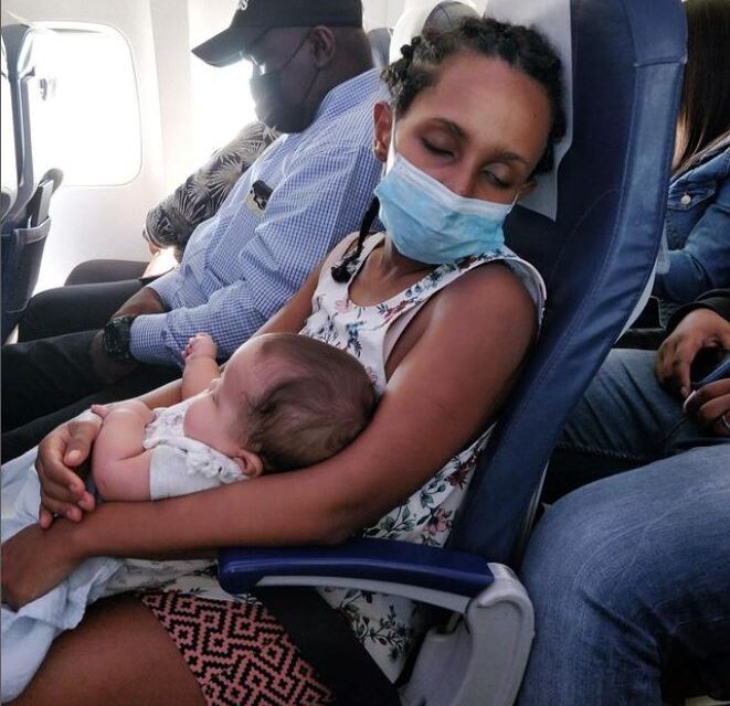 A black mother with her infant both sleeping on the plane